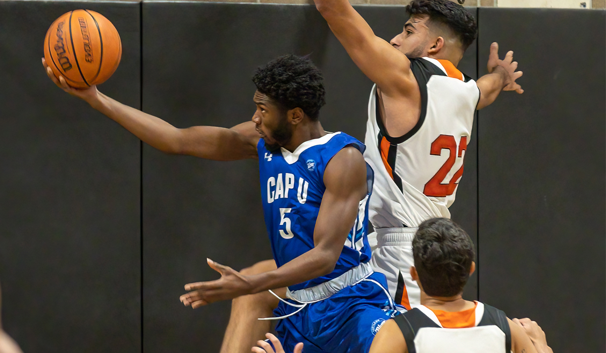 Tyrone Asenoguan attacks the basket with Jas Dhudwal guarding the rim. CapU and Langara split their weekend set at Langara.