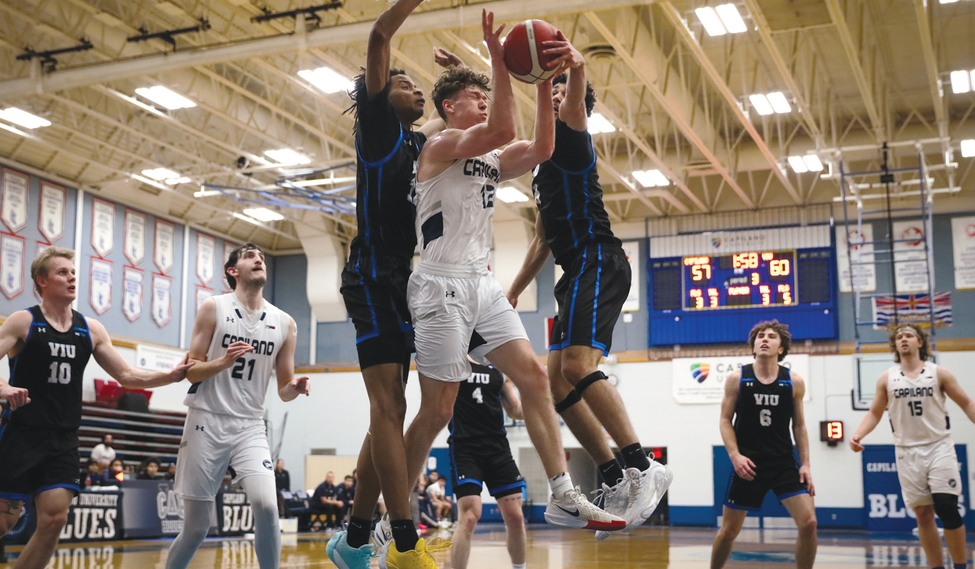 Kash Lang runs into a pair of VIU defenders as part of a 94-80 loss to the Mariners Friday night at the Centre for Sport and Wellness.