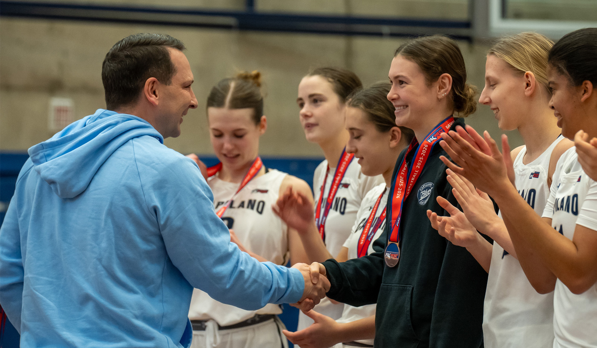 Capilano University's new president Dr. Jason Dewling presents the bronze medals to the Blues women's basketball team. (Chris Raeside photo)