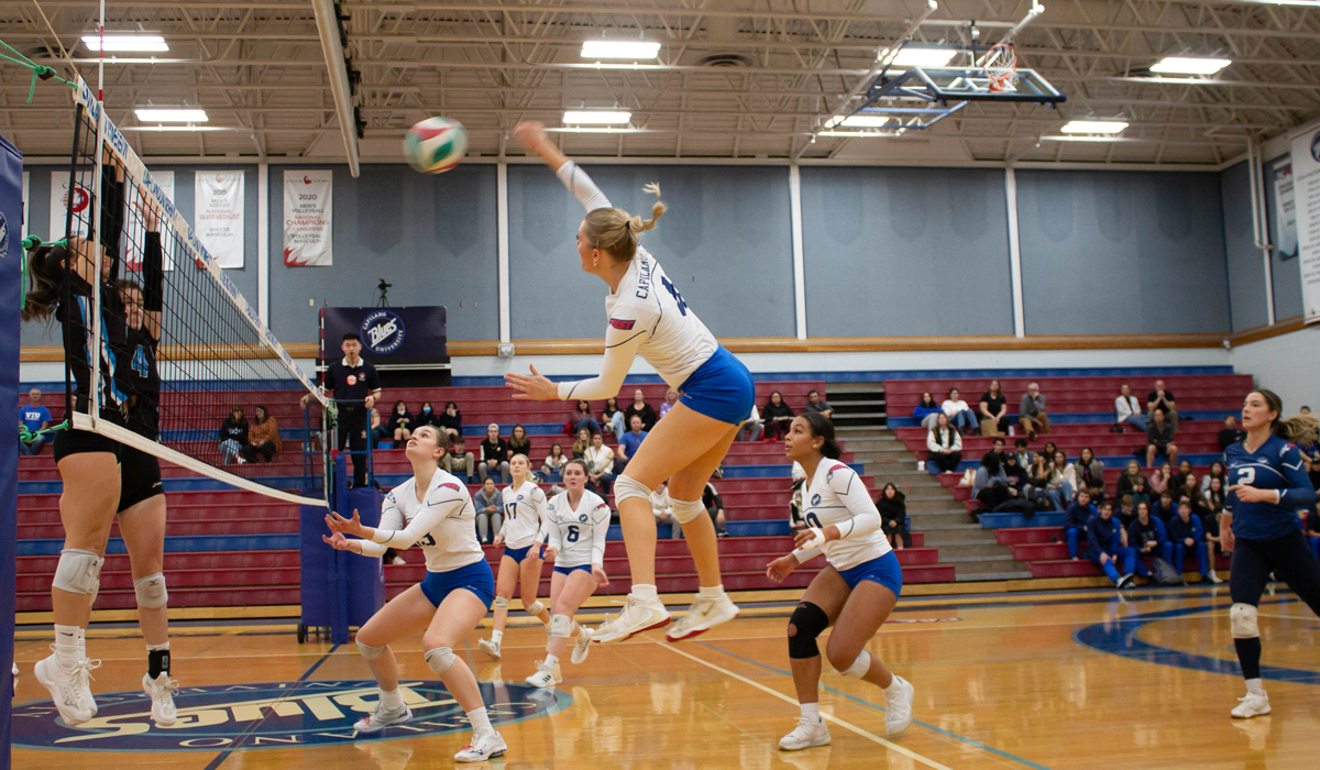 Courtney Muller takes a swing with a pair of VIU opponents putting up a block. CapU took the nation's No. 1-ranked team to five sets Friday at the Centre for Sport and Wellness.
