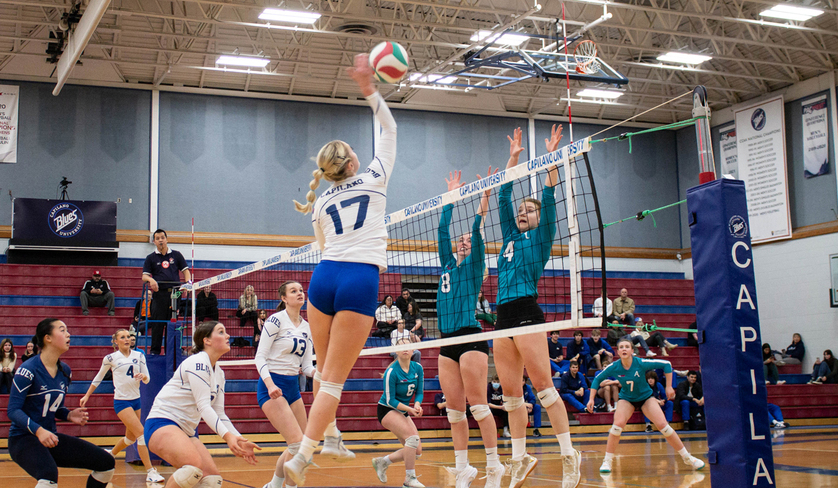Annika Kuznik gets up for a big swing against a pair of College of the Rockies blockers Friday at CapU.